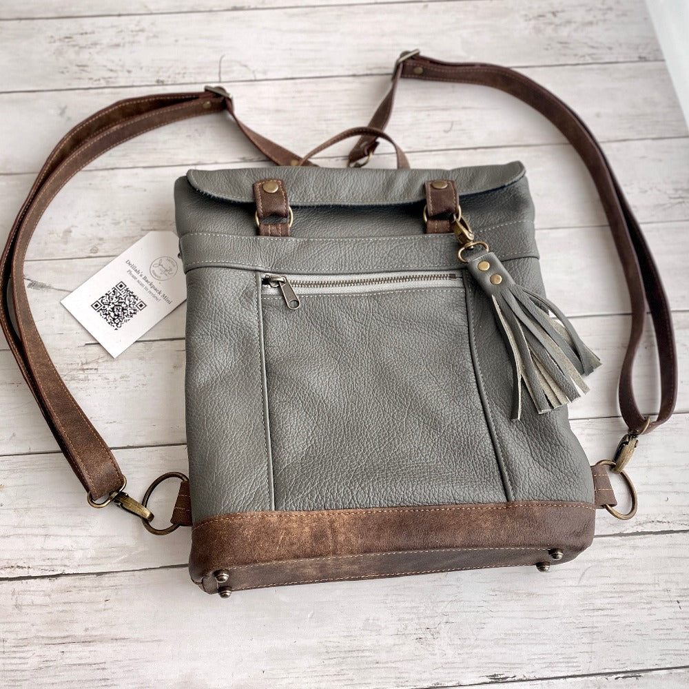 Delilah's Custom Backpack Mini in Steel leather with Antique Brown leather accents, Steel tassel, antique brsas hardware, and crossbody upgrade.